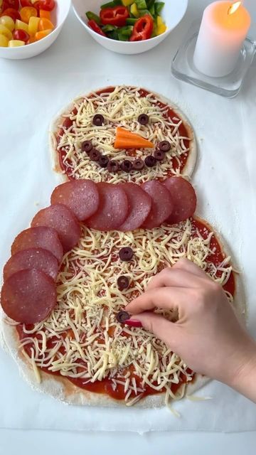 someone making a snowman pizza with pepperoni, cheese and ham on it for christmas