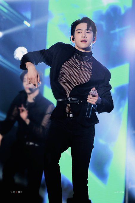 the man is standing on stage with his hands in his pockets and wearing a black outfit