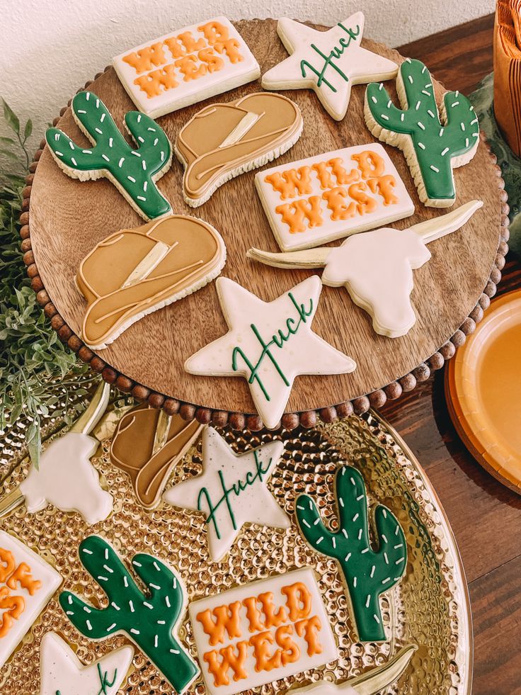 some decorated cookies are sitting on a wooden table next to a plate with cactus decorations