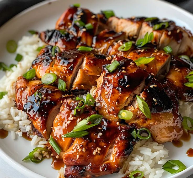 a white plate topped with chicken and rice covered in sesame seed sprinkles