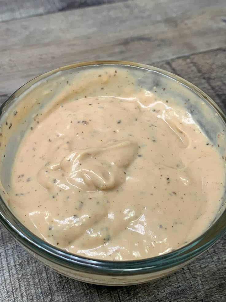 a glass bowl filled with sauce on top of a wooden table