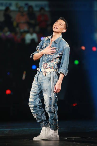 a man standing on top of a stage with his hands in his pockets and smiling