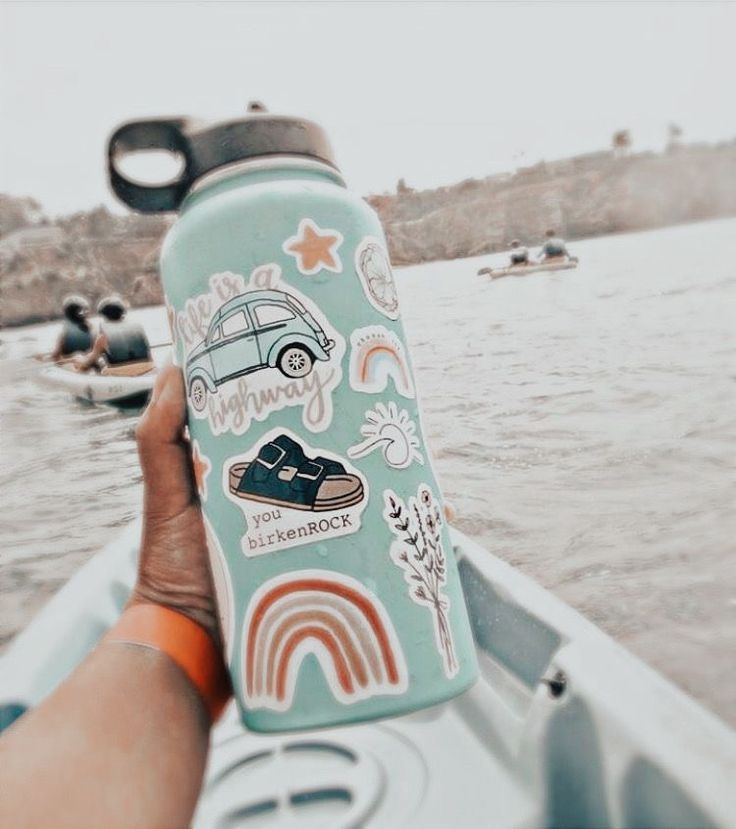 someone is holding up a water bottle with stickers on it while in a boat