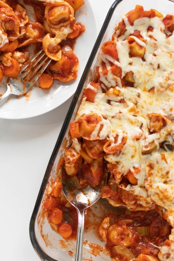 a casserole dish filled with pasta and sauce next to a plate of macaroni and cheese