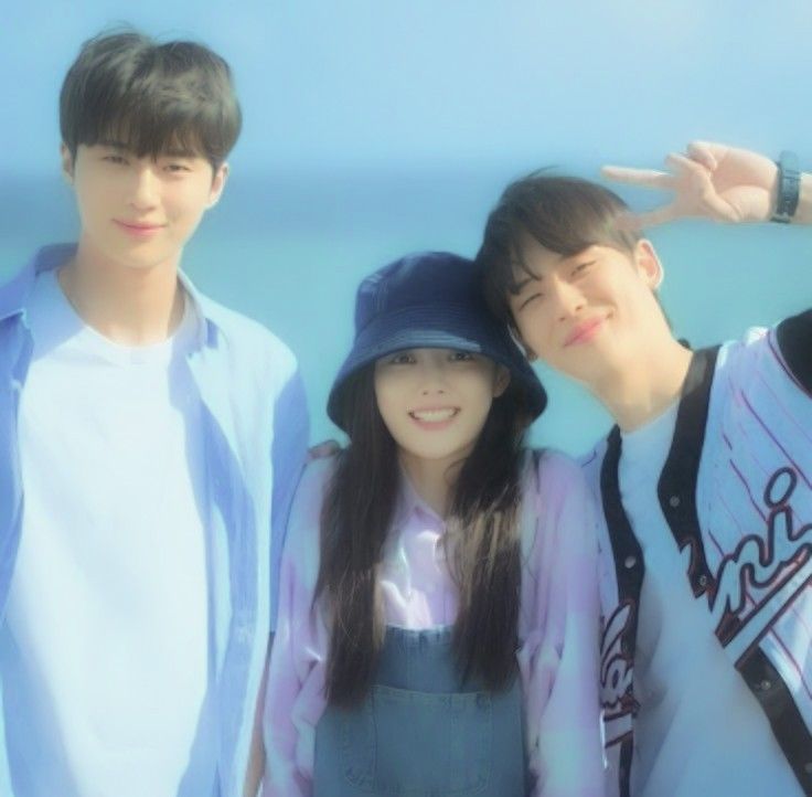 three young people standing next to each other near the ocean