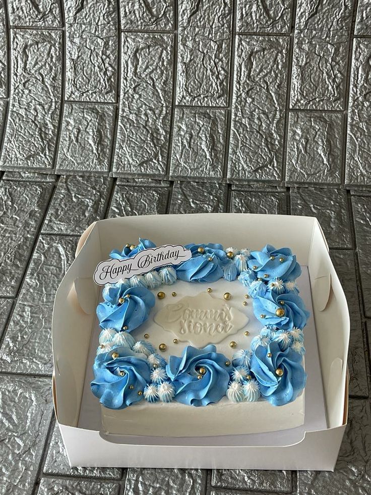 a birthday cake in a box with blue and white flowers on it's side