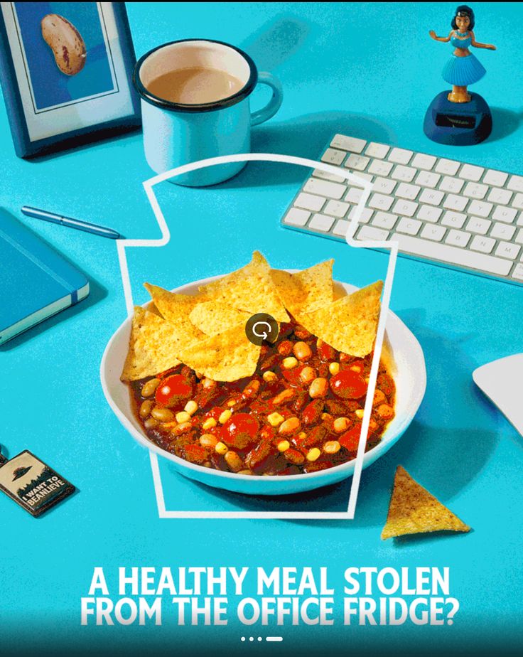 a bowl of chili with corn chips and tortilla chips in front of a keyboard