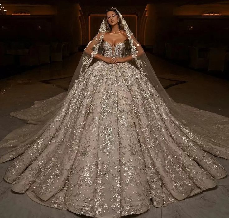 a woman in a wedding dress standing next to a chandelier with lights on it