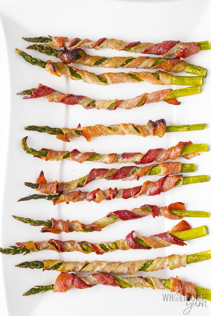 asparagus and bacon skewers arranged on a white platter, ready to be served