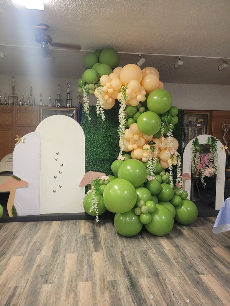 an arrangement of balloons and greenery on the floor