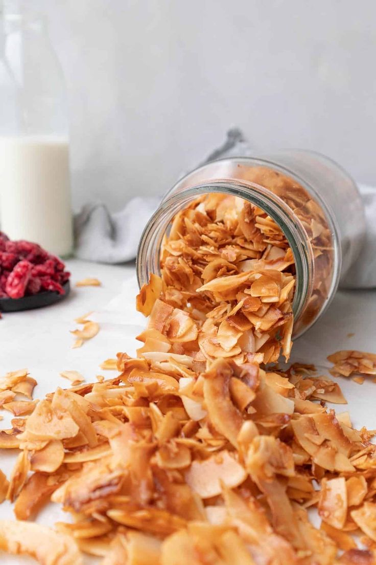 a glass jar filled with granola next to some raspberries