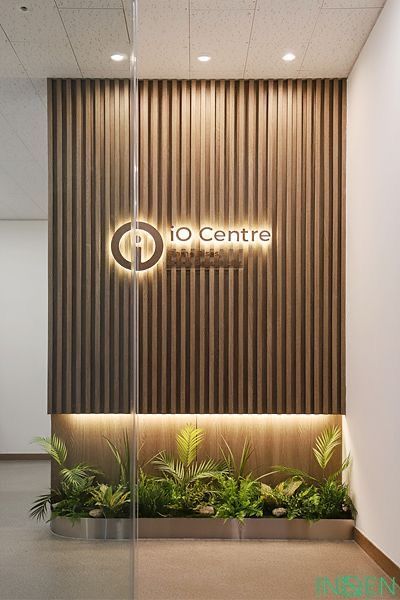 the entrance to an office building with plants and lights on it's side wall