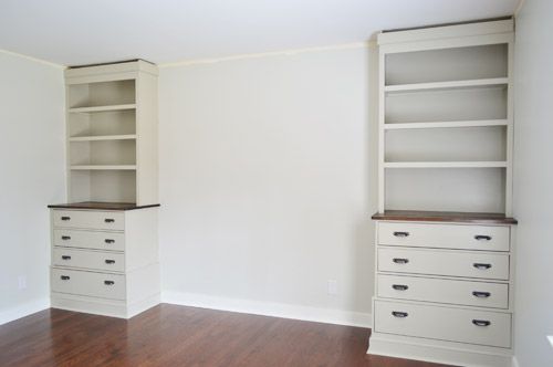 an empty room with white cabinets and wood floors