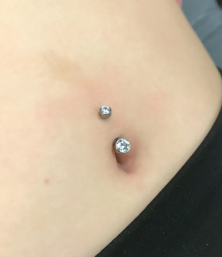 a woman's stomach with two piercings on it