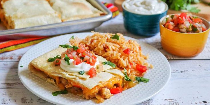 mexican food with rice and salsa on a white plate next to a bowl of sour cream