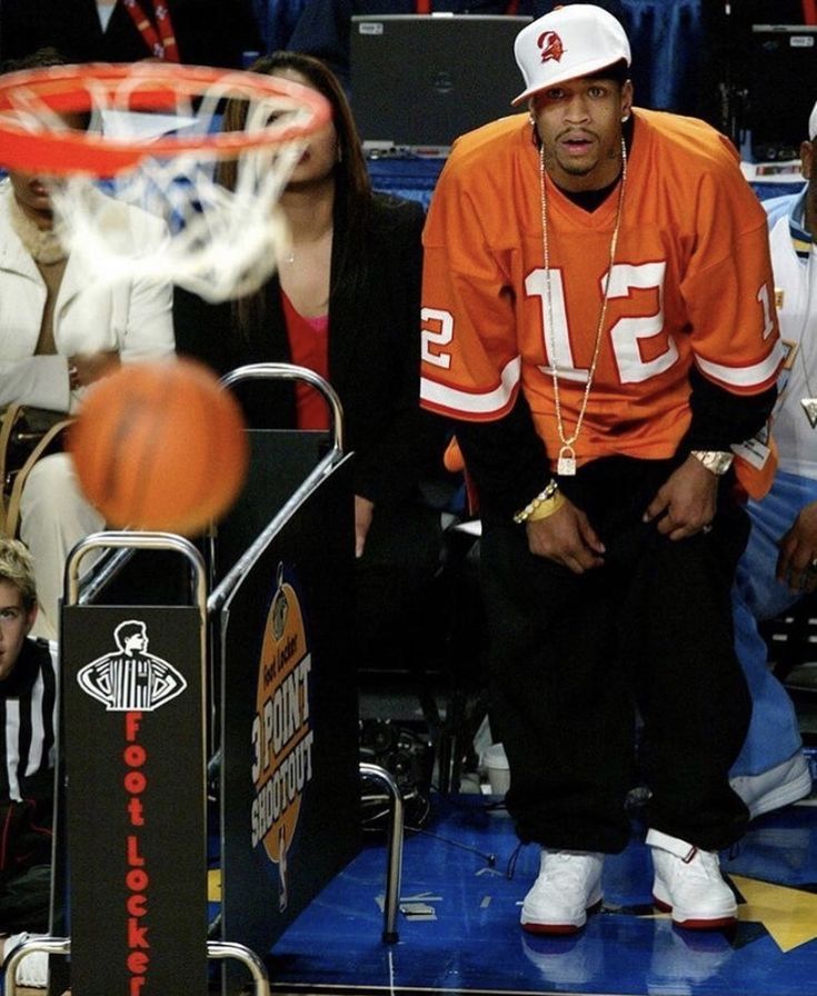 a basketball player is sitting on the sidelines with his head in the air as people watch