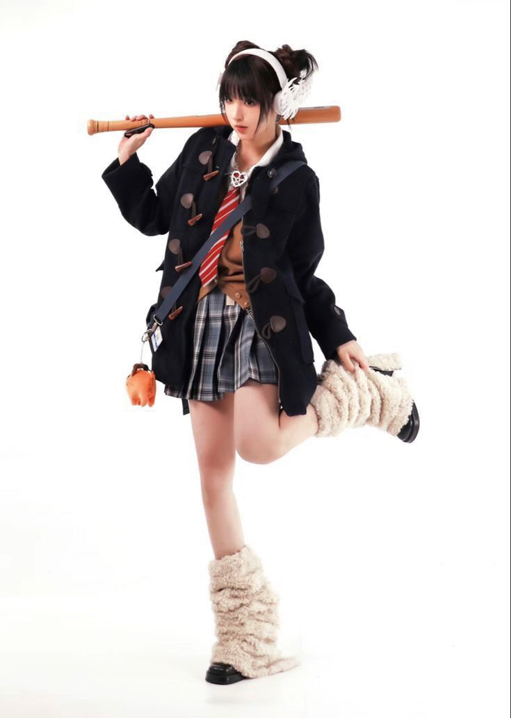 a woman in a skirt and jacket holding a baseball bat over her head while standing on one leg