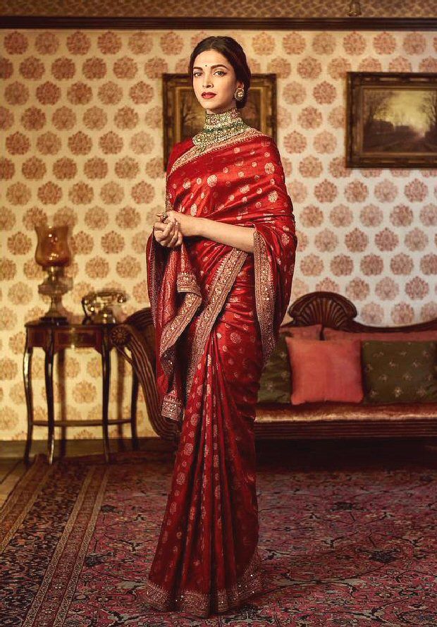 a woman in a red sari standing next to a couch