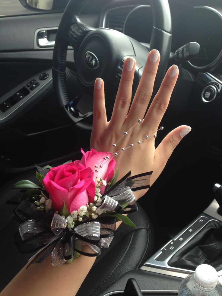 a woman's hand on the steering wheel of a car with flowers and pearls