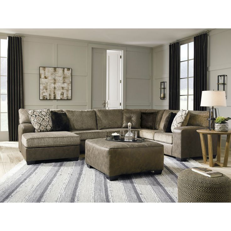 a living room scene with focus on the sectional sofa and footstool in the center