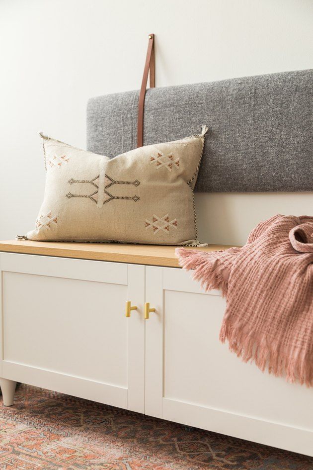 a white bench with two pillows on top of it and a pink throw pillow next to it