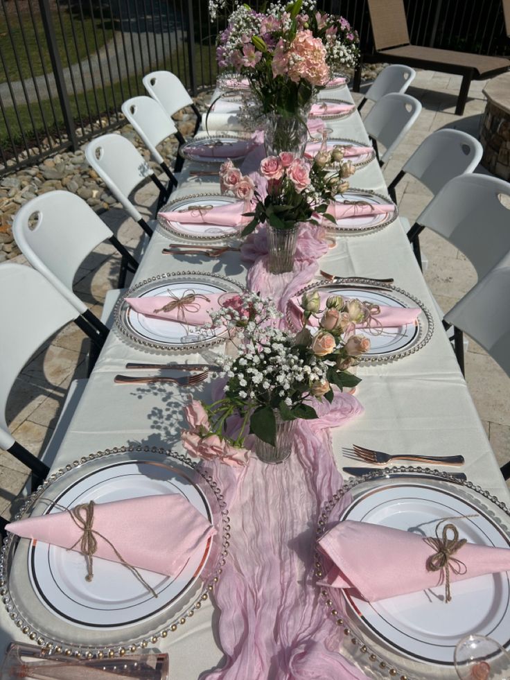 the table is set with pink napkins and place settings