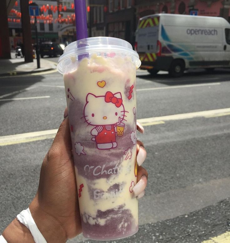 someone holding up a hello kitty drink on the street