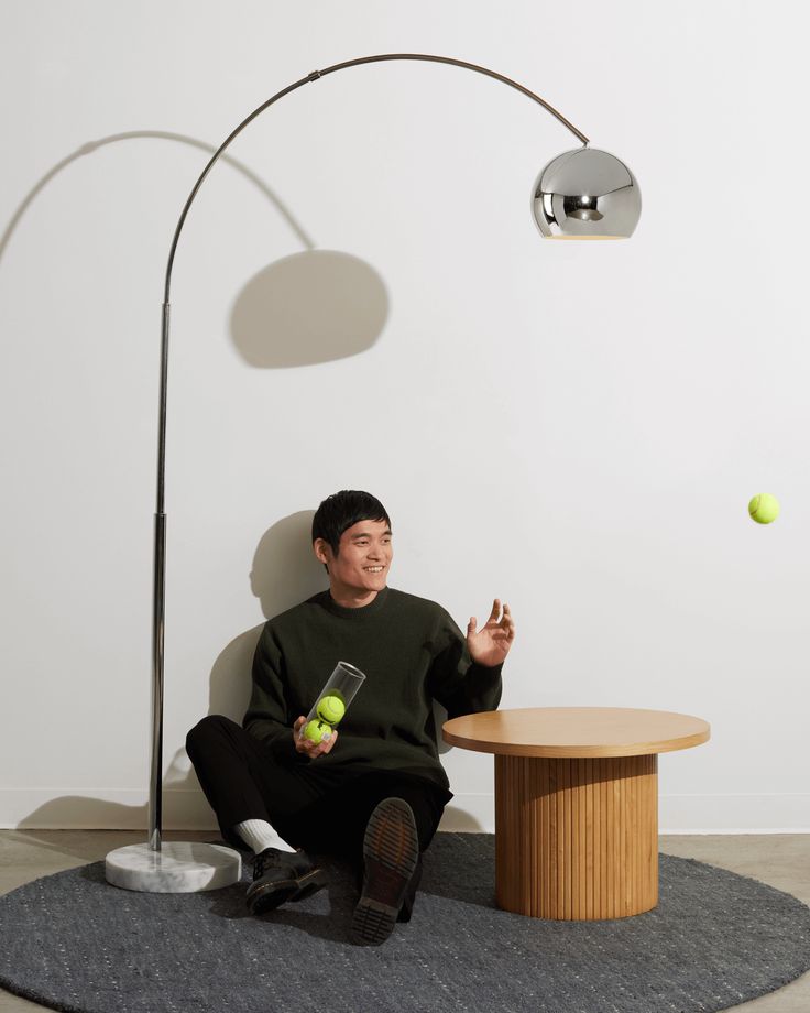 a man is sitting on the floor with an apple in his hand while holding a tennis ball