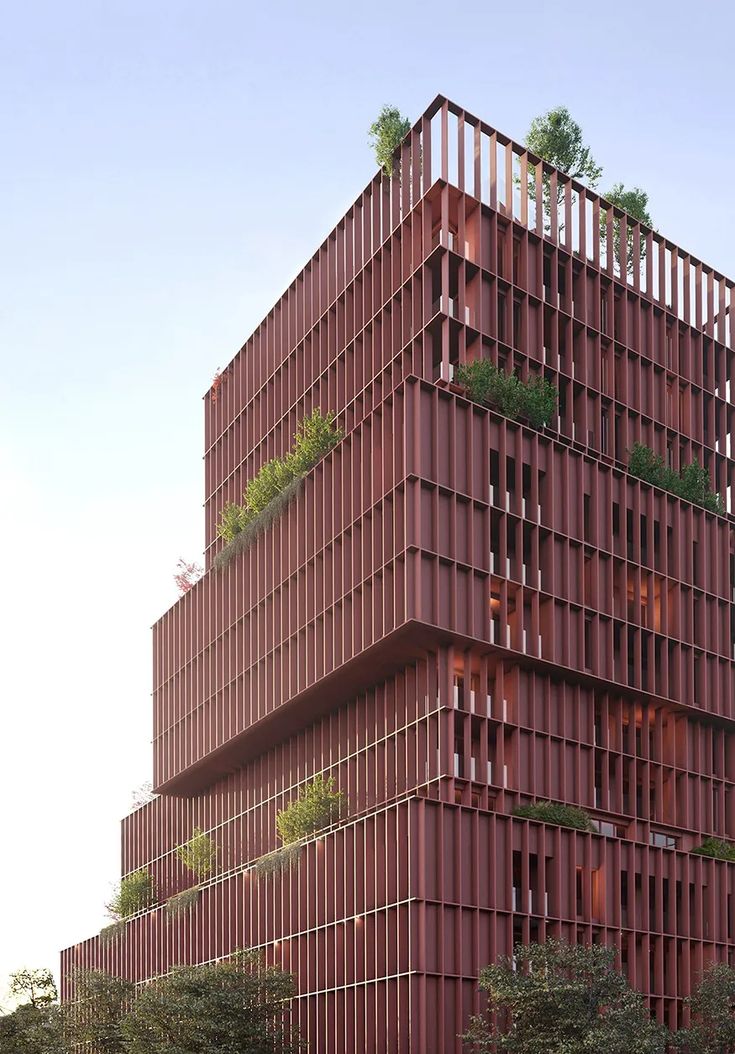 a tall red building with lots of windows and plants on the top of it's balconies