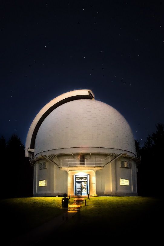 a large white dome sitting on top of a lush green field under a night sky