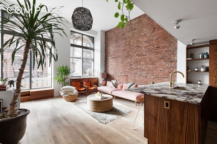 a living room filled with furniture next to a kitchen and dining room table in front of a brick wall