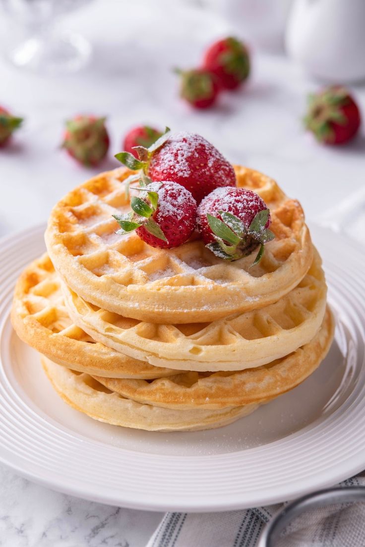 a stack of waffles topped with strawberries on top of a white plate