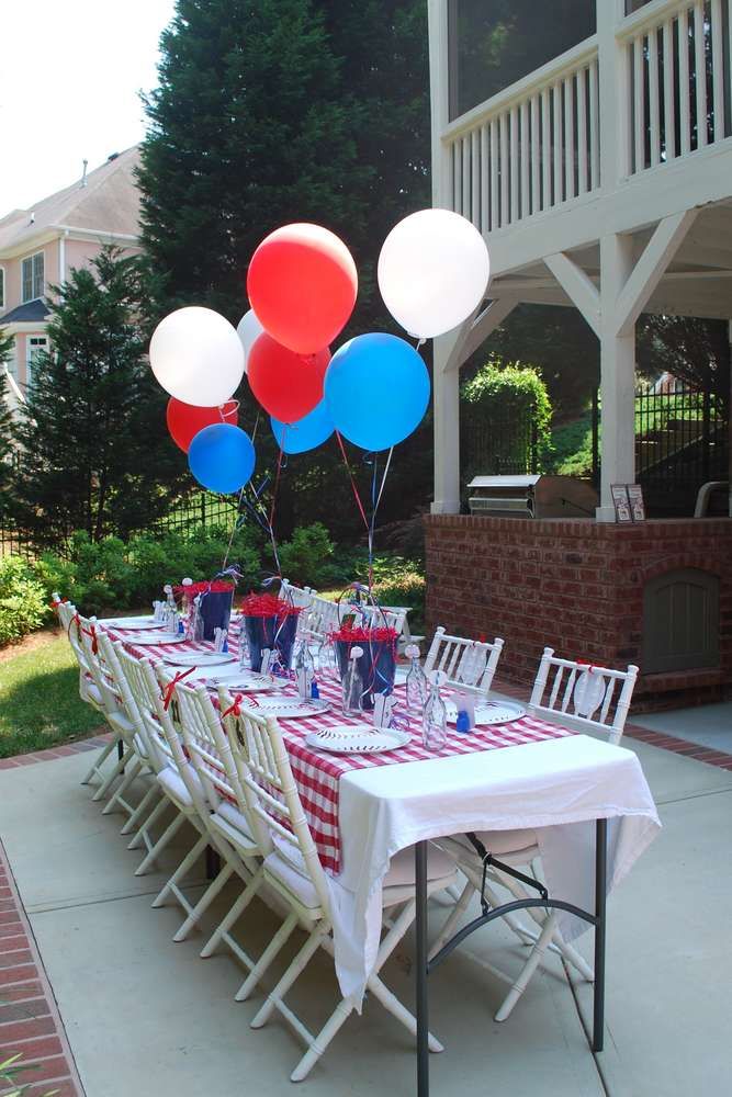 a table set up with balloons for a fourth of july party in front of a house