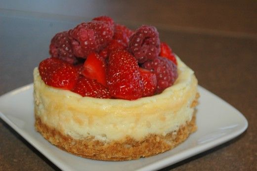 a cheesecake topped with raspberries on a white plate