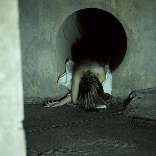 a woman is laying down in a tunnel with her head on the ground and hands behind her back