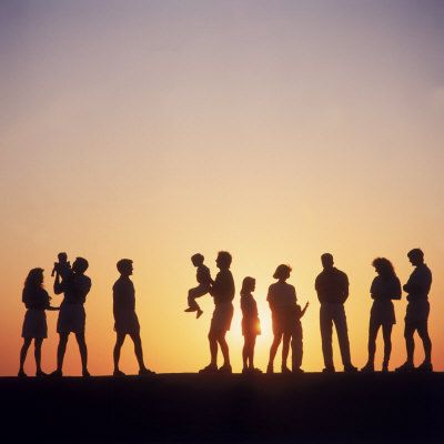 a group of people standing next to each other on top of a hill at sunset