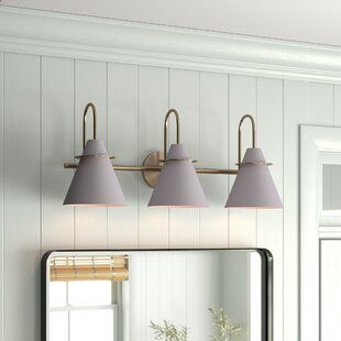 a bathroom vanity with three lights and a mirror on the wall above it, along with a potted plant