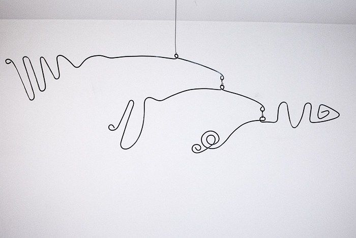 a black and white drawing of a car hanging from a wire on the wall in a room