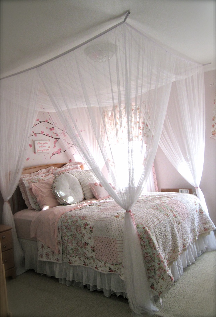 a white canopy bed sitting in a bedroom next to a window