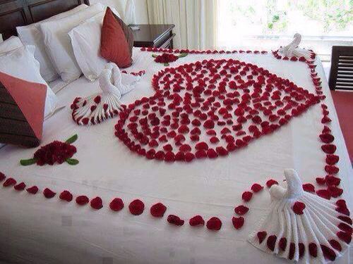 a bed decorated with red flowers and petals