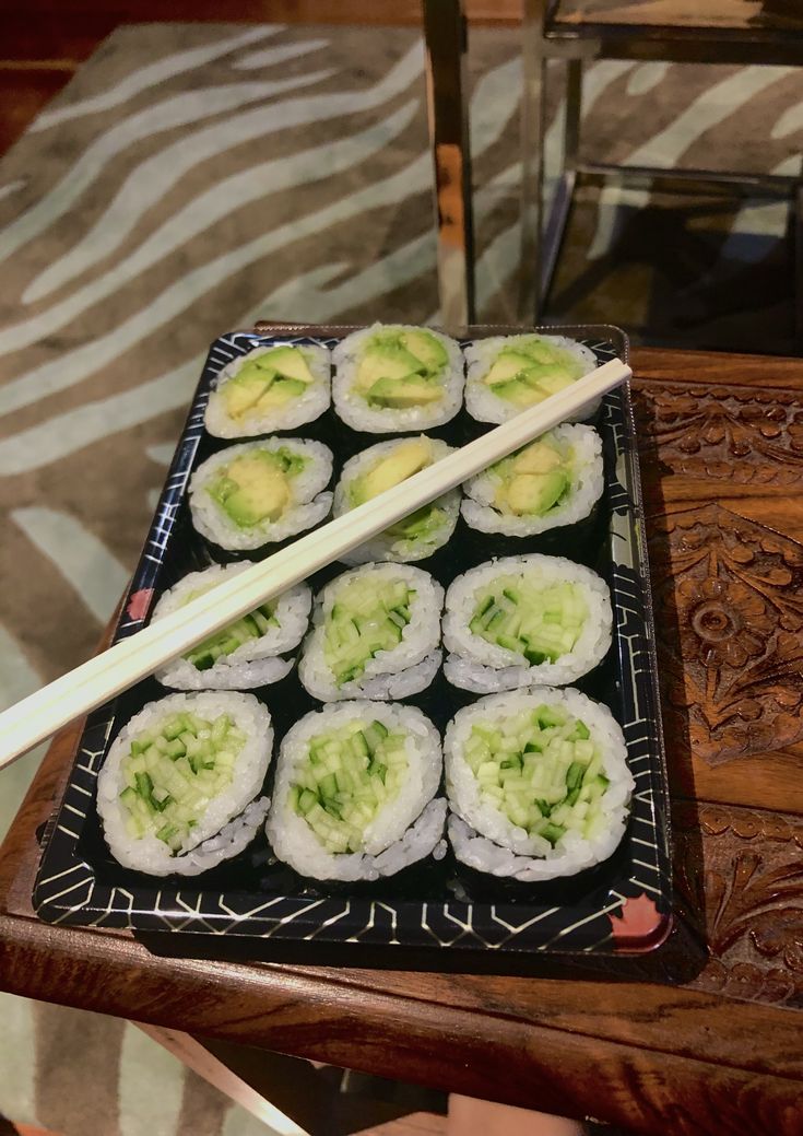 sushi on a tray with chopsticks sitting on top of it, ready to be eaten