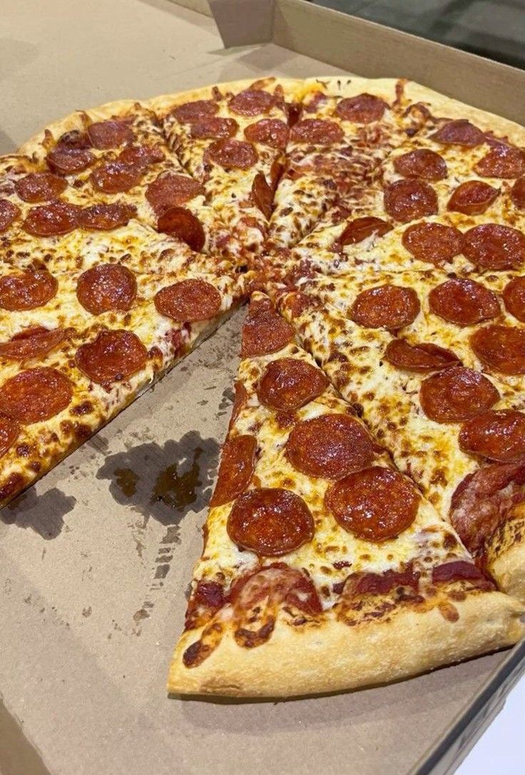 a pepperoni pizza sitting on top of a cardboard box with one slice taken out