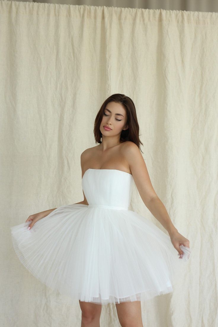 a woman in a short white dress is posing for the camera with her hands on her hips