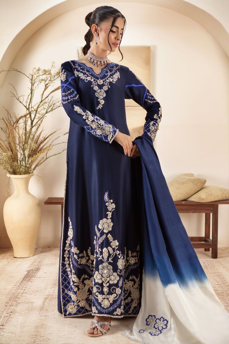 Make a Bold style statement this wedding season with our stunning Kaftan, cut from Pure Raw silk featuring 3D resham floral embroidery accentuated with zardozi, Swarovski, crystals, beads & Sequins . Flattering cut, floor length & stunning motifs along the front hem of shirt have designed to have heads turning everywhere. Paired with pure Raw Silk straight pant featuring and two tone dyed dupatta featuring embroidered motifs for uber chic look. Kaftan Fabric: Pure 80gms Raw SilkKaftan Length: 55” (Slightly customisable, mention in order notes)Pant Fabric: Pure 80gms Raw SilkDupatta Fabric: Pure Medium SilkColor: Navy Blue This outfit is fully lined, lining in sleeves is complimentary mention in order notes if required. Please refer Size Guide Before selecting size For Customised measuremen Designer Outfit, Embroidered Motifs, Crystals Beads, Wedding Bridal Party, Bridal Party Dresses, Bold Style, Pakistani Designers, Style Statement, Raw Silk