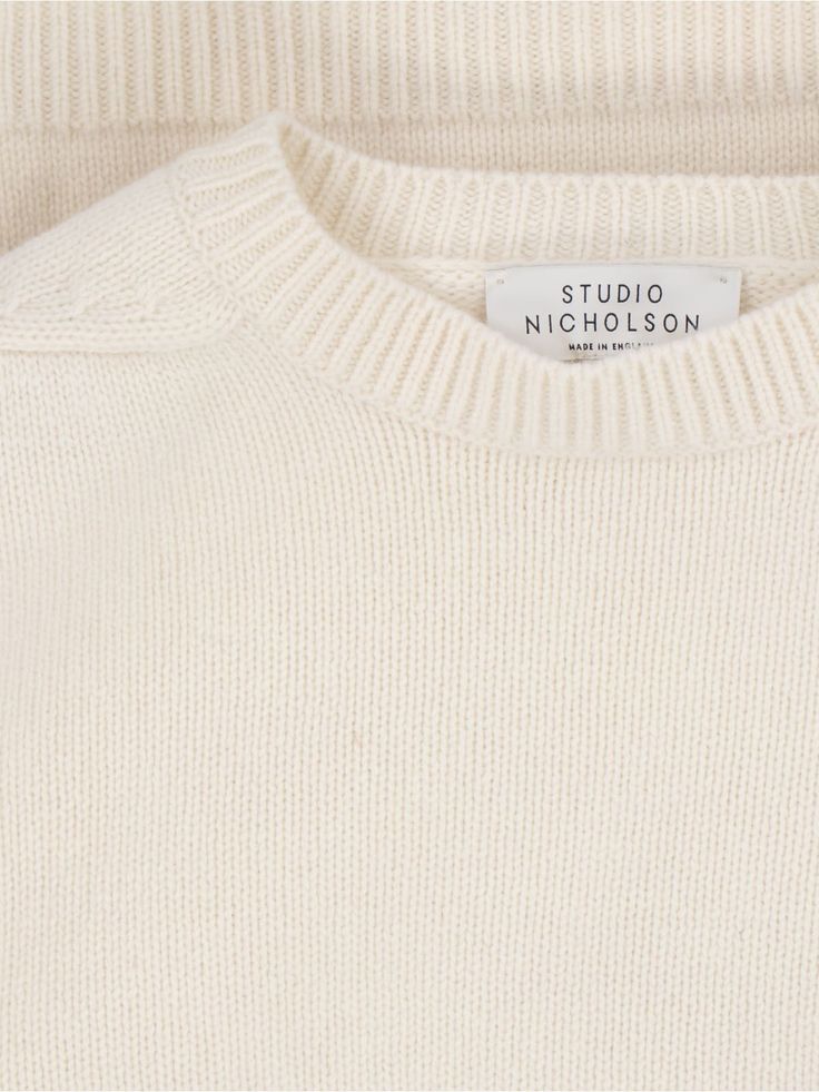 Studio Nicholson 'Hemyl' basic sweater in cream wool with crew neck, dropped shoulders, ribbed trims, straight hem. Composition: 100% Lamb Wool Classic White Sweater With Ribbed Neckline, White Ribbed Cashmere Sweater, Classic Winter White Sweater With Ribbed Cuffs, White Sweater With Ribbed Neckline For Work, White Wool Crew Neck Sweater, Classic Oversized Sweater With Ribbed Neckline, Cream Ribbed Crew Neck Sweater, Winter White Crew Neck Cashmere Sweater, Winter White Cashmere Crew Neck Sweater