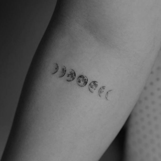 a woman's arm with phases of the moon tattoo on it