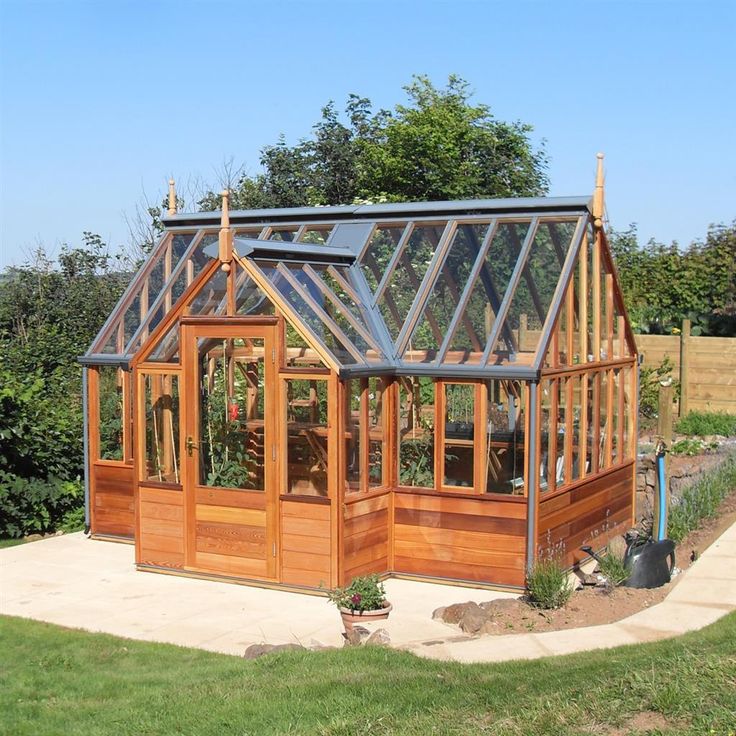 a small wooden greenhouse in the middle of a yard