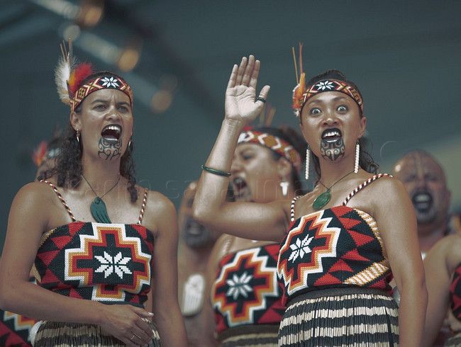 three women in native garb singing and holding their hands up