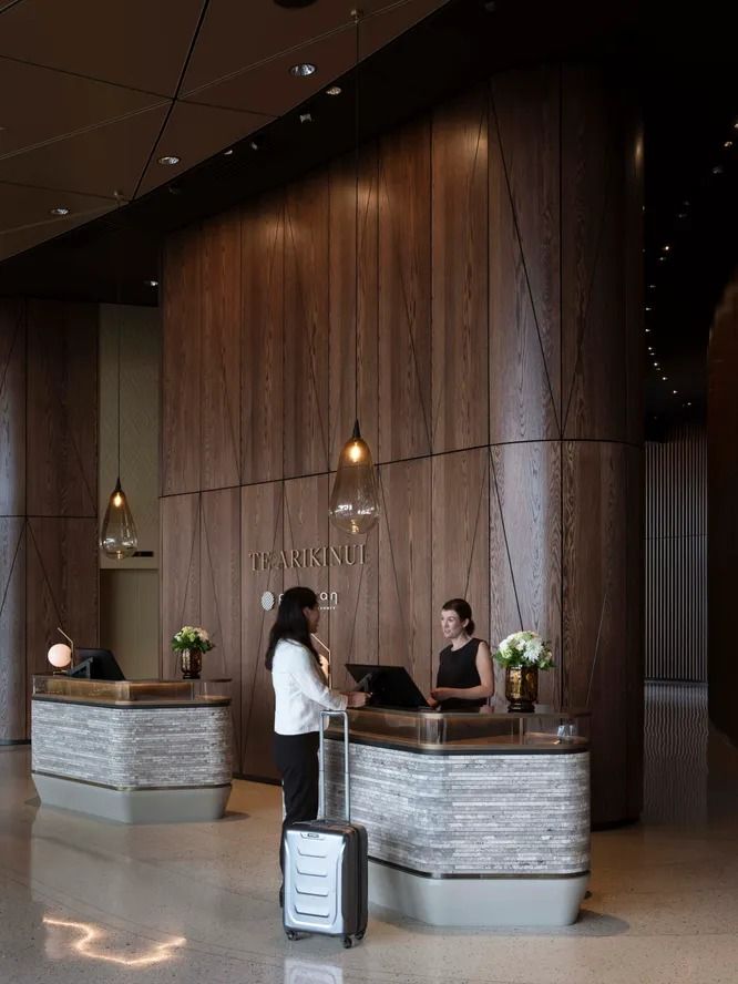 a woman standing at the front desk of a hotel