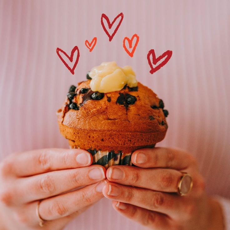 a woman holding a muffin with chocolate chips and butter on top in her hands